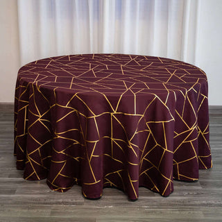 Round burgundy tablecloth with golden geometric pattern draped over a table.