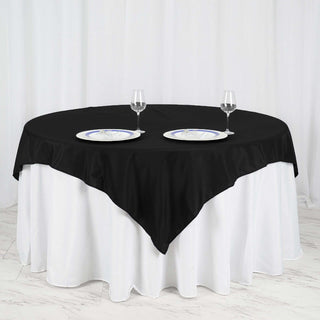 Black round tablecloth elegantly draped on a white table with plates and glasses.