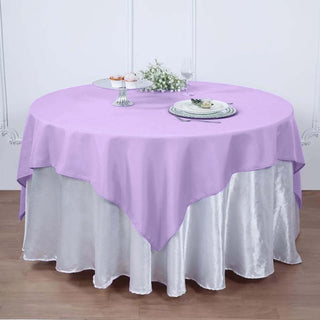 Lavender round tablecloth draped over a silver table skirt in a styled setting.