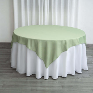 Round table with a green and white tablecloth on a wooden floor.