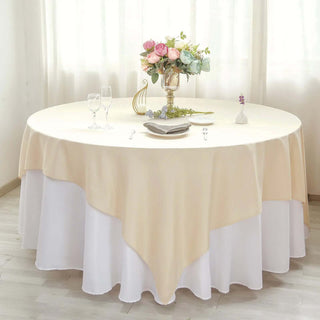 Elegant round table set with a cream tablecloth and floral centerpiece.
