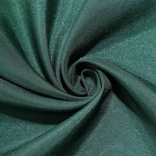 Dark green fabric with a smooth texture in a swirling pattern.