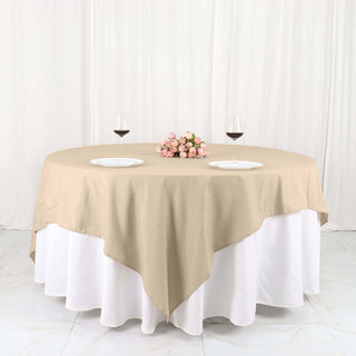 Beige tablecloth draping over a round table with plates and wine glasses.