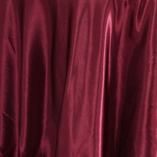 Burgundy satin fabric with smooth, glossy texture draping elegantly.