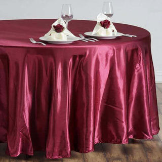 Burgundy tablecloth draped over a round table set for dinner.