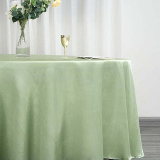 Green tablecloth draped elegantly over a table with a vase and glass on top.