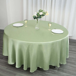 Round green tablecloth on a dining table with floral centerpiece and table settings.