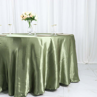 Elegant olive green satin tablecloth draped over a round table with floral centerpiece.