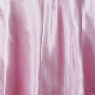 Pink satin fabric draped and wrinkled, showcasing its smooth texture.