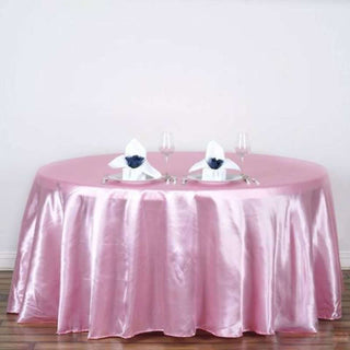Pink satin tablecloth with elegant table setting and napkins.