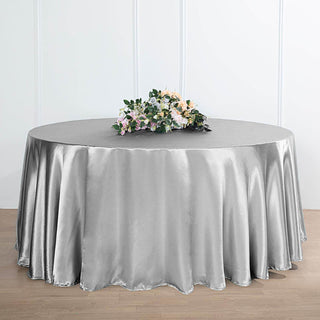 Silver round tablecloth with elegant drape and floral centerpiece.