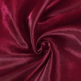 Burgundy satin fabric swirled in a circular pattern.