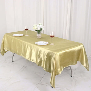Gold satin tablecloth draped over a table set with plates and wine glasses.