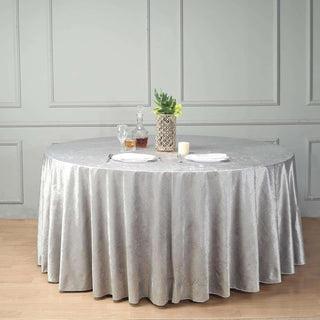 Round silver tablecloth draped over a dining table with elegant dinner setup.