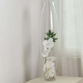 Clear vase with white orchids and green leaves, elegantly displayed.