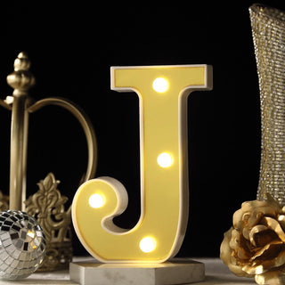 Yellow illuminated letter "J" marquee sign on a decorative table.