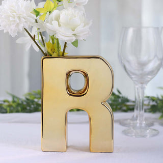 Gold letter "R" vase with white flowers, elegant decor piece.