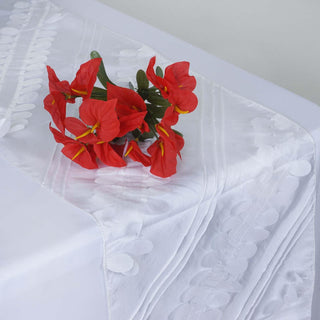 Red artificial flowers on a white tablecloth.