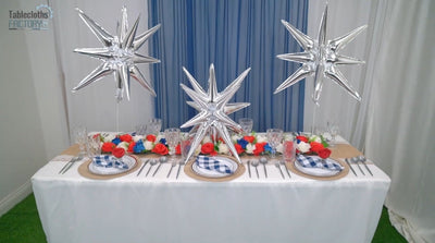 Finished 4th of July table setup with silver star balloons and patriotic flowers.