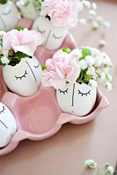 Painted Easter egg vases with flowers in a pink carton