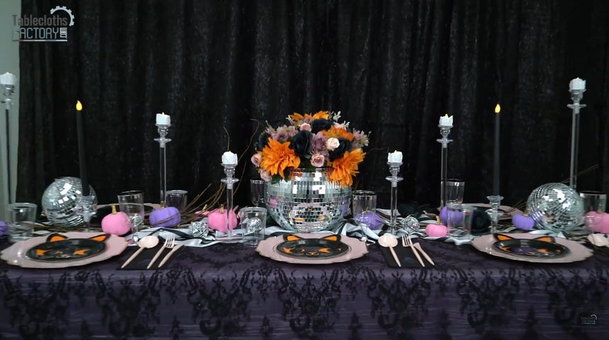 Halloween table decor with disco ball vase, floral centerpiece, and taper candles.