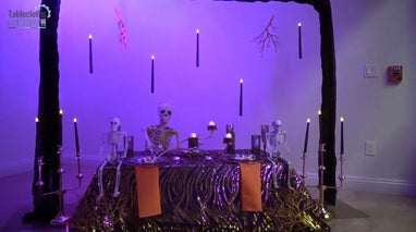 Spooky Halloween table setup with skeletons, floating candles, and elegant black and gold decor.