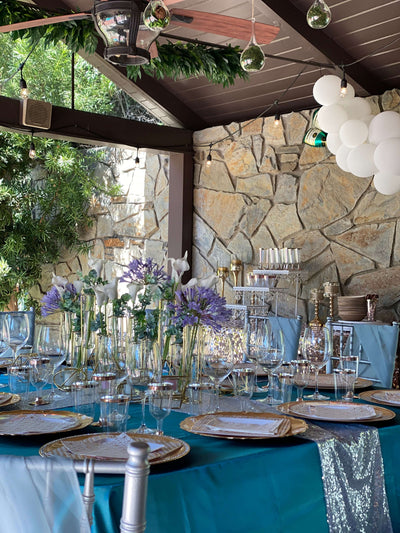 Outdoor table set with teal linens and purple floral centerpieces