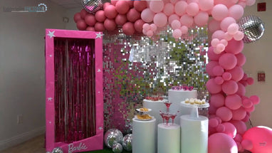 Pink Barbie-themed party display with balloon arch and dessert stands