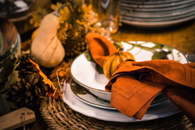 Fall table setting with orange napkin and pumpkin