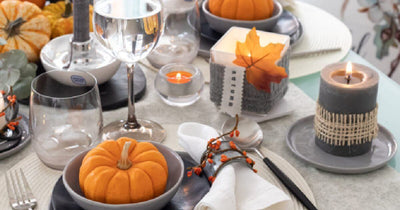 Fall tablescape with pumpkins, candles, and autumn leaves