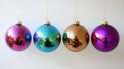 Four colorful disco ball ornaments hanging against a white wall