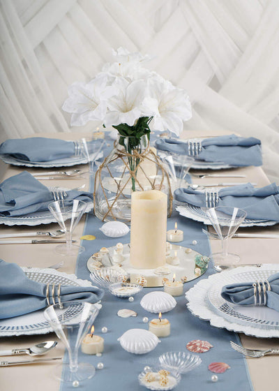 Beach-themed table setting with blue napkins and seashell decor
