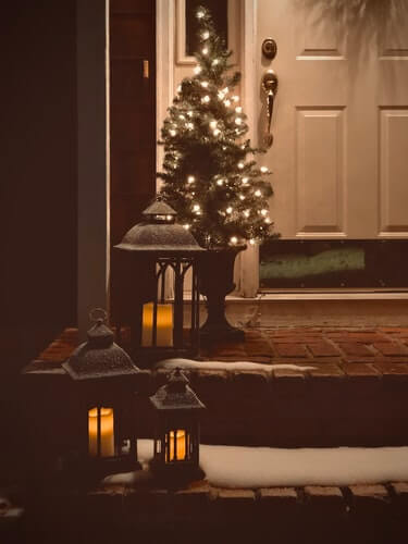 Front porch with lit Christmas tree and lanterns