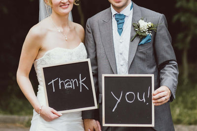 Bride and groom holding thank-you signs