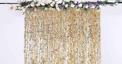 Gold sequined backdrop with floral garland