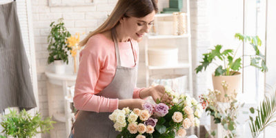 Woman arranging artificial flowers in a bright shop
