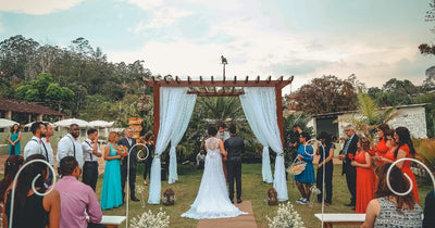 Wedding ceremony under a wooden arch with guests standing nearby