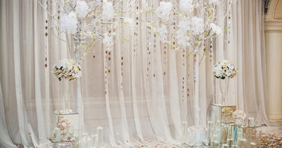 Sheer curtain backdrop with white floral arrangements