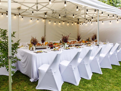 Outdoor reception table under a tent with white chair covers