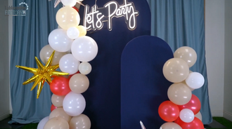 Completed 4th of July backdrop with balloon garland, gold and silver stars, and a 'Let's Party' LED sign.