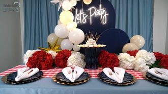 Stunning 4th of July table decor with 'Let's Party' neon sign, balloon garland, and vibrant red and white floral arrangements.