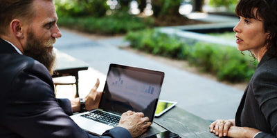 Two people discussing business outdoors at a laptop