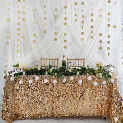 Gold sequin table with white drapes and hanging discs
