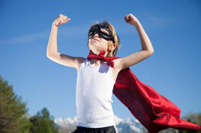 Child dressed as a superhero with red cape