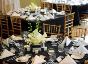 Wedding reception tables with black linens and gold chairs
