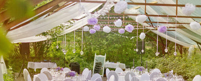 Ceiling drapes with hanging pom-poms over reception tables