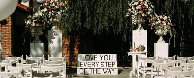 Wedding ceremony with floral pillars and sign