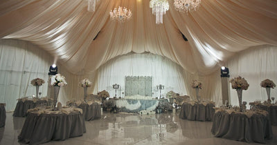 Elegant wedding reception tent with draped ceiling and floral tables