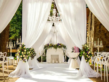 White draped wedding ceremony with chandeliers and floral arrangements