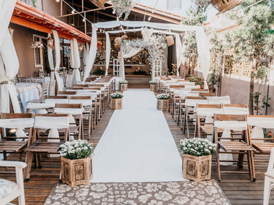Outdoor wedding ceremony setup with white aisle runner and draped canopy